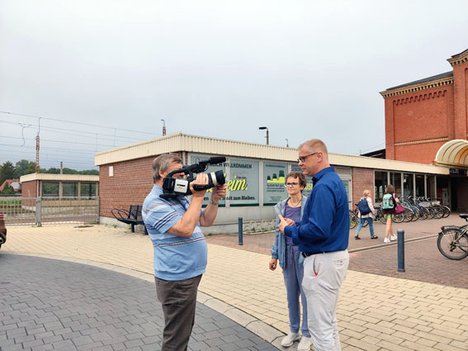 Auf dem Bild ist Anke Schwarzenberg und Andreas Büttner vor dem Bahnhof Guben im Interview mit Stadtfernsehn zu sehen