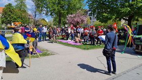 Das Bild enthält Bäume in einem Park und viele Menschen. Auf der linken Seite Menschen in den Nationalfarben der Ukraine, im Vordergrund Anke Schwarzenberg bei ihrer Rede